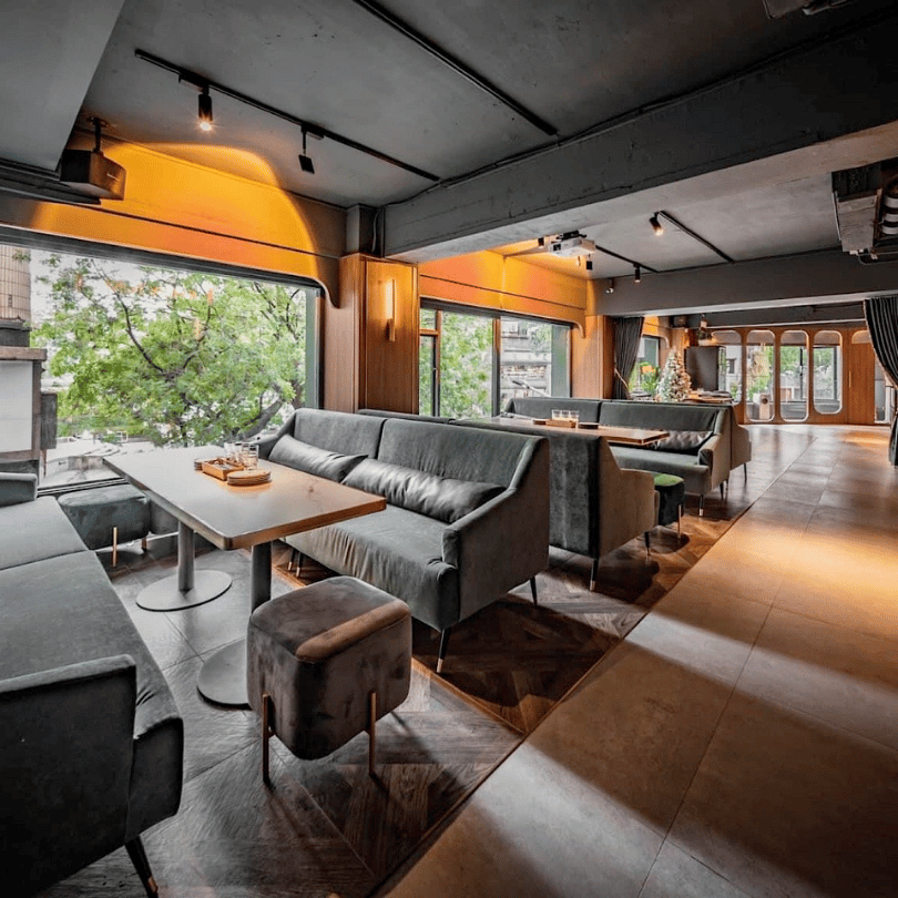 台北信義區 Joiny Taipei 招台北餐酒館店內環境,寬敞舒適的灰色系沙發座席與大片落地窗,提供高品質的台北約會與包場聚餐空間