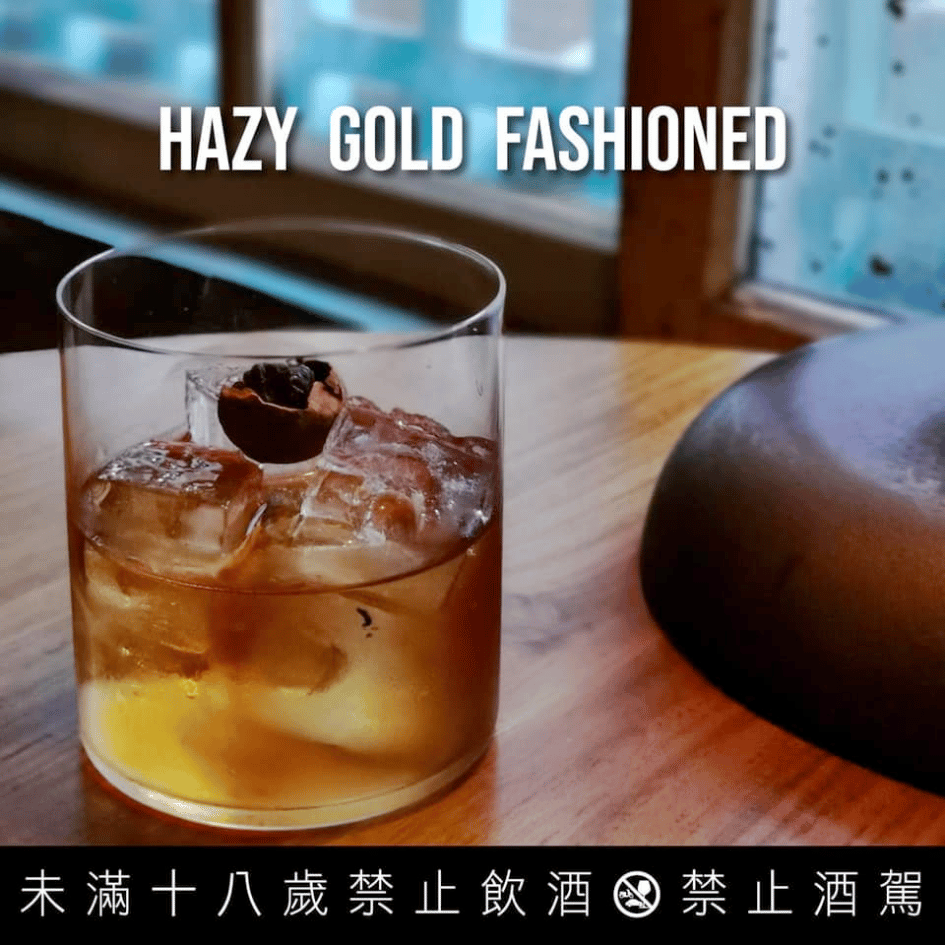 The Public House 特色調酒 Hazy Gold Fashioned，晶瑩冰塊搭配質感玻璃杯與木質桌面襯托
